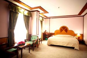 a bedroom with a bed and chairs and a window at The Surya, Cochin in Angamali