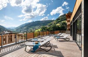 uma varanda com cadeiras e mesas num edifício em Les Chalets de Joy em Le Grand-Bornand