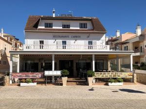 a large white building with benches in front of it at APARTAMENTOS CABRITA in Olhos de Água