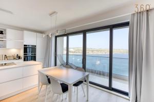 une cuisine avec une table et des chaises ainsi qu'une grande fenêtre dans l'établissement Designer 2BR home with Stunning views in St Pauls by 360 Estates, à San Pawl il-Baħar