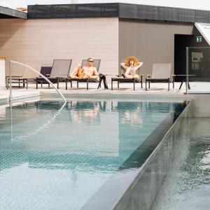 Dos personas sentadas en sillas junto a una piscina en Olivia Balmes Hotel, en Barcelona