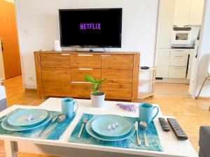 a living room with a table with plates and a tv at Special BLUE TIGER Apartment Basel, Messe Kleinbasel 10-STAR in Basel