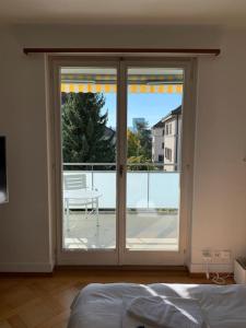 a bedroom with a large sliding glass door with a balcony at Sunny studio in the city center (Oken1) in Zürich
