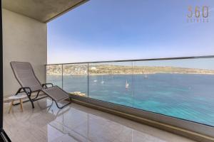 - un balcon avec deux chaises et une vue sur l'eau dans l'établissement Designer 2BR home with Stunning views in St Pauls by 360 Estates, à San Pawl il-Baħar
