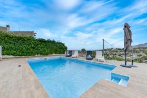 a swimming pool with chairs and an umbrella on a patio at Villas Guzman - Alex in Benissa