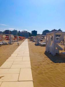 una spiaggia sabbiosa con tavoli e sedie di Hotel Alessi** Rimini a Rimini