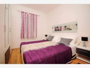1 dormitorio con 1 cama grande con manta morada en Apartmani Mastrinka, en Vinišće