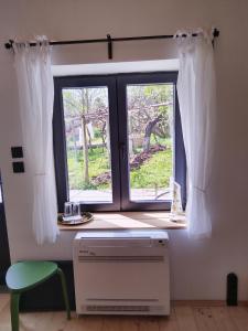 a window with white curtains and a green chair at Под шарената сянка in Kŭrpachevo