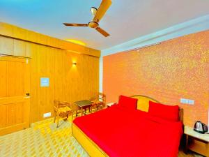 a bedroom with a red bed and a ceiling fan at Grand view lodge and Restaurant Dharamshala - Partial Prepayment required to confirm booking in Dharamshala