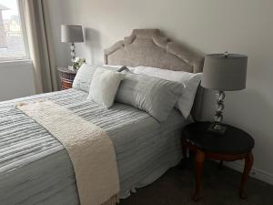 ein Schlafzimmer mit einem Bett und einem Tisch mit einer Lampe in der Unterkunft Brantford King Bed Near it All in Brantford