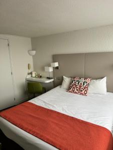 a bedroom with a large bed with a red blanket at The Originals City - Hotel Restaurant A Pic in Cherbourg en Cotentin