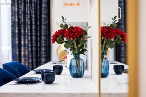 a table with two blue vases with red flowers at Amethyst Apartments - Tatra in Budapest