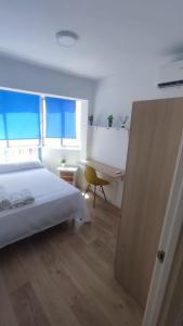 - une chambre avec un lit blanc et un bureau dans l'établissement La Reina II R&R, à Almería