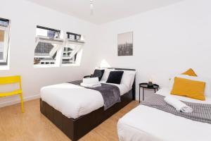 a bedroom with two beds and a yellow chair at Shoreditch Apartments by DC London Rooms in London