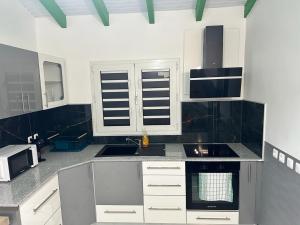 a kitchen with white cabinets and a sink at Lacazavanoo in Baillif