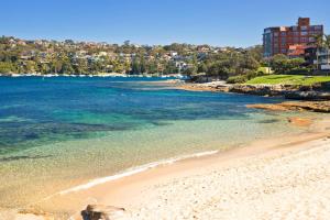 a beach with the ocean and buildings in the background at The Sands - Convenient Location in Sydney