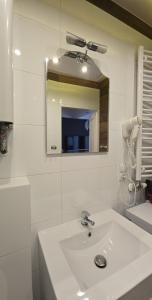a white bathroom with a sink and a mirror at Apartament Pod 12 in Bielsko-Biała