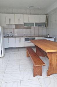 cocina con mesa de madera y banco de madera en Suítes na Barra da Lagoa, en Florianópolis