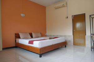 um quarto com uma cama com uma parede laranja em Maewang Resort em Lampang