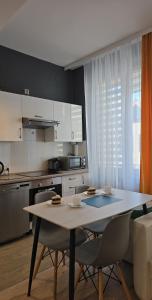 una cocina con mesa y sillas y una cocina con armarios blancos. en Apartament Pod 12, en Bielsko-Biala