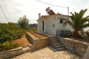 a small white house with a stone wall at Villa Matina Skiathos in Troulos