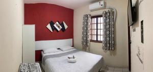 1 dormitorio con 2 camas y pared roja en Pousada Córdoba Cabo Frio, en Cabo Frío