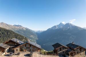 um grupo de edifícios com montanhas ao fundo em Residence Alpen Lodge em La Rosière