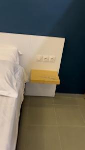 a bed with a night stand next to a blue wall at Appartement Luxueux de 3 pièces - Cotonou in Cotonou