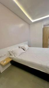 a white room with a bed and a table at Appartement Luxueux de 3 pièces - Cotonou in Cotonou