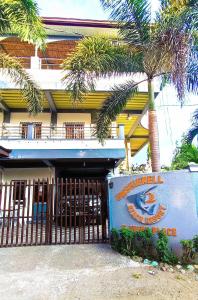 a building with a gate and a palm tree at Emshienell Beach Resort and Event Place in Zambales