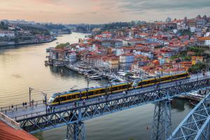 Holiday Inn Express Porto - Boavista, an IHG Hotel في بورتو: قطار على جسر فوق نهر