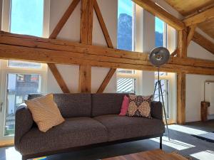 un sofá en una sala de estar con techos de madera. en Neu! Ferienwohnungen im Lüftlmalereck, Hennalahaus en Oberammergau