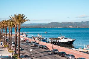 a boat is docked next to a street with cars at Albamarina in SantʼAntìoco