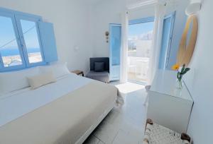 1 dormitorio blanco con 1 cama y 1 silla en Villa Fotini en Firostefani