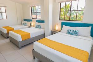 1 dormitorio con 2 camas y 2 ventanas en Hotel Roca Sunzal en La Libertad