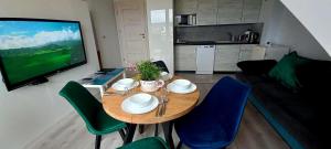 a living room with a table and chairs and a television at Apartament Pogodny in Łeba