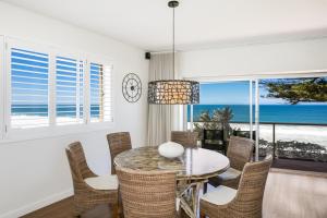 un comedor con mesa y sillas y el océano en Beachfront Dream - Direct Beachfront en Narrabeen