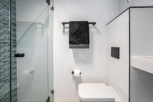 a white bathroom with a toilet and a shower at Yulunga - Direct Beachfront in Narrabeen