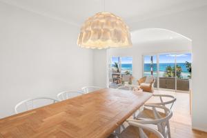 a dining room with a table and chairs and the ocean at Sweeping Panoramic Views - Brand New Beach House in Curl Curl