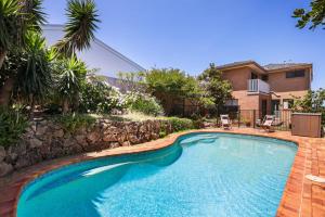 a swimming pool in a yard with a stone wall at Sweeping Panoramic Views - Brand New Beach House in Curl Curl
