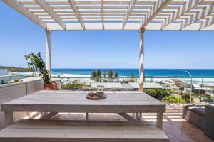a picnic table on a patio with a view of the beach at Sweeping Panoramic Views - Brand New Beach House in Curl Curl