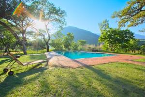 a pool in a park with a bench in the grass at Elangeni Holiday Resort in Waterval Boven