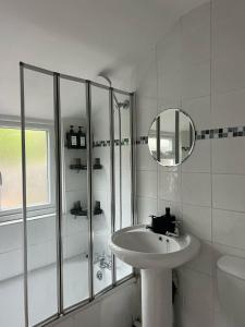 a white bathroom with a sink and a shower at Rickmansworth Lodge in Watford