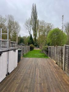 a wooden deck with a fence and a yard at Rickmansworth Lodge in Watford