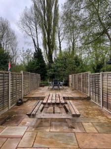 a wooden deck with two chairs and a picnic table at Rickmansworth Lodge in Watford