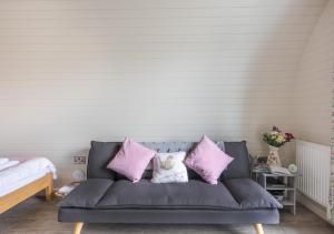 Un sofá gris con almohadas rosas en un dormitorio en Paradwys, en Llanfyllin