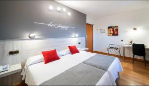 Habitación de hotel con 1 cama con 2 almohadas rojas en Hotel Mozárbez Salamanca, en Mozárbez
