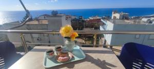 a table with a vase with a donut and flowers on a balcony at Ionian View in Gjilek