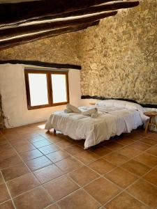 1 dormitorio con 1 cama en una pared de piedra en Casa puebla de Arenoso II Rental Holidays REF.066, en La Pobla d'Arenós (Puebla de Arenoso)