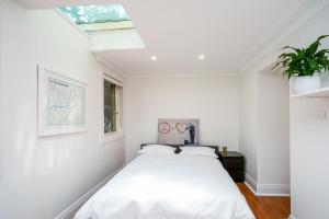 Dormitorio blanco con cama y tragaluz en Bower House en Sídney